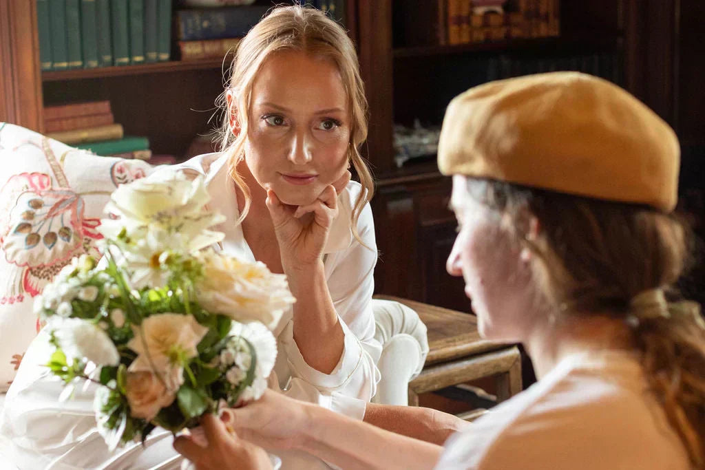 Portland wedding florist from Kvetka Flower tying ribbon on bridal bouquet while consulting with bride about wedding flower costs