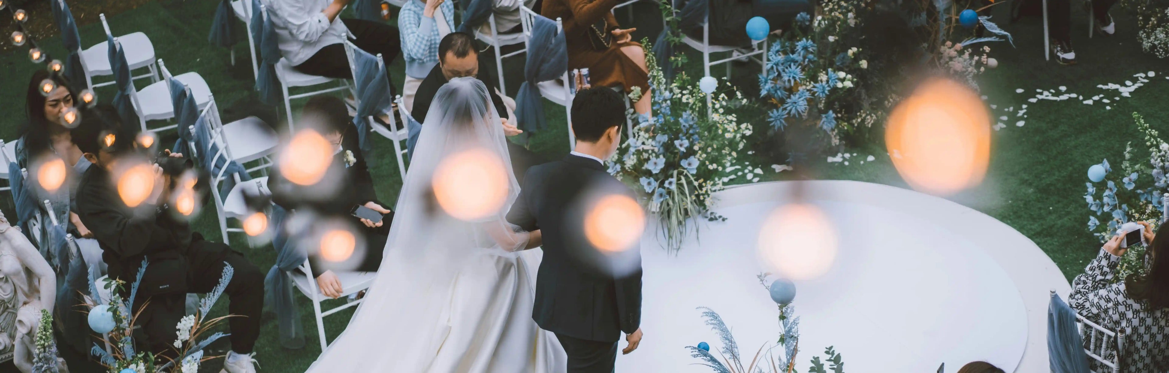 Wedding ceremony with bride and groom at the altar, guests seated around, and floral decorations.