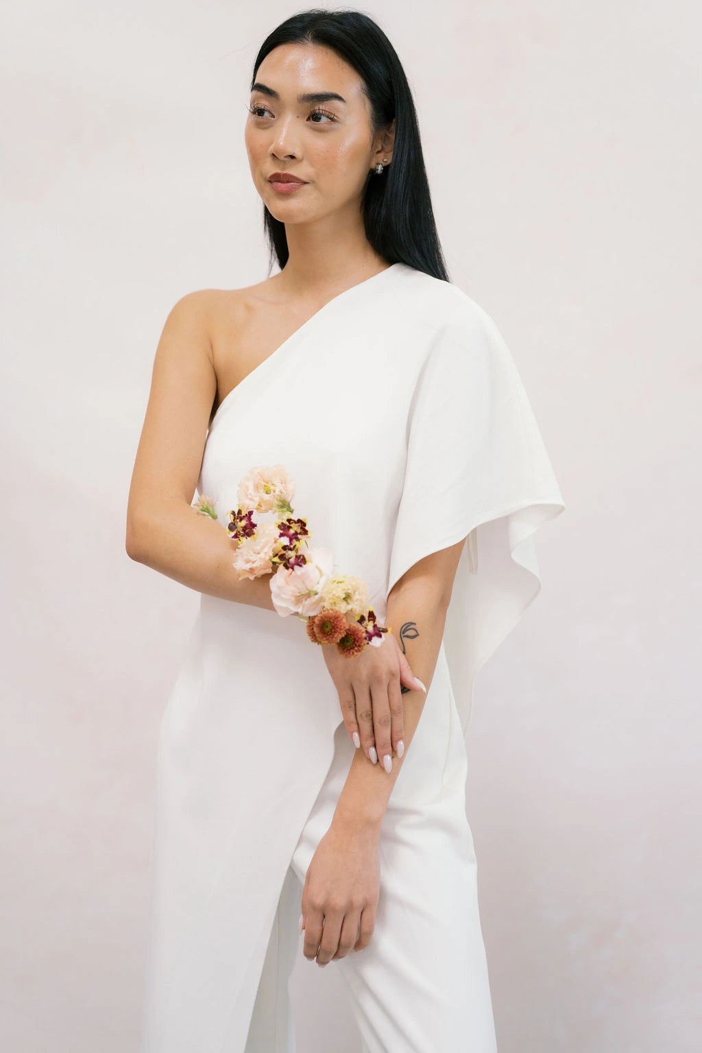 Avant-garde forearm corsage with mini orchids and carnations on bride in white dress by Kvetka Flower