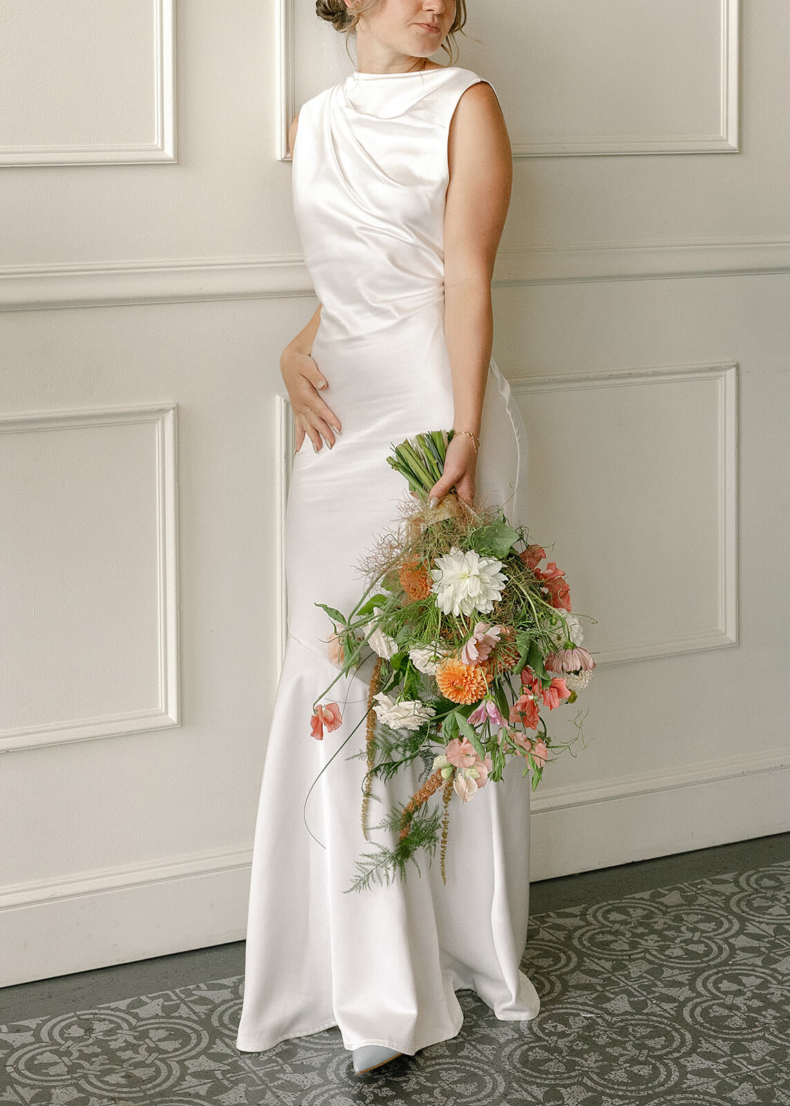 Bride in satin dress holding natural, airy bouquet with dahlias and cosmos by Kvetka Flower