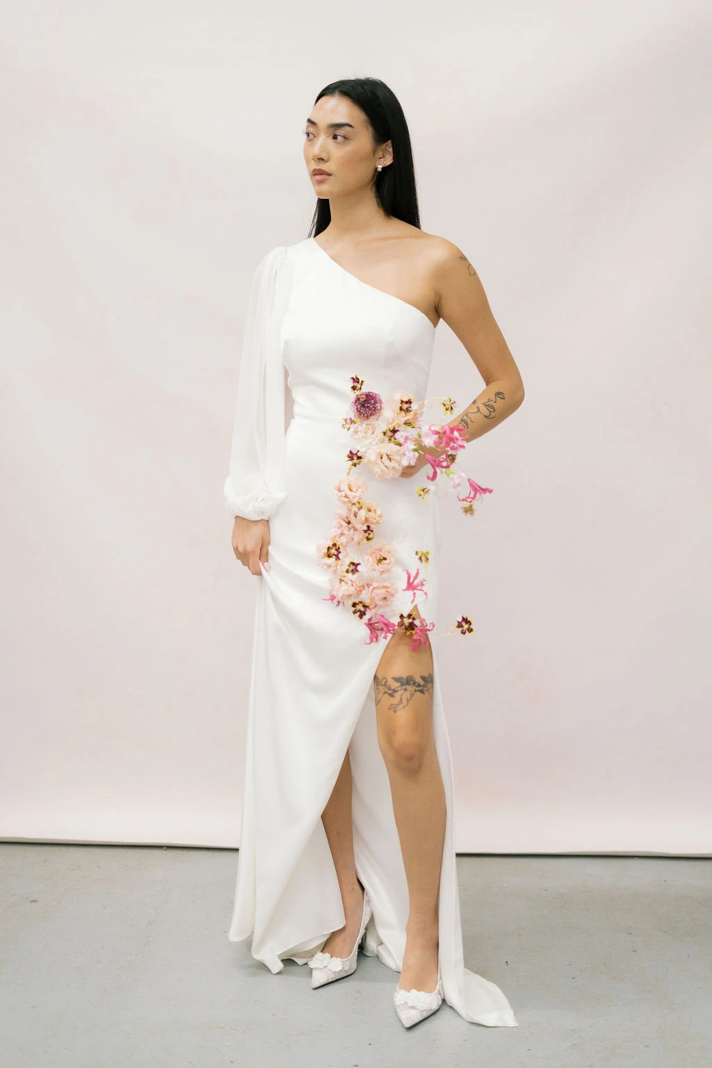 Bride in white one-shoulder dress holding cascading wire-frame bouquet with lisianthus and nerine by Kvetka Flower