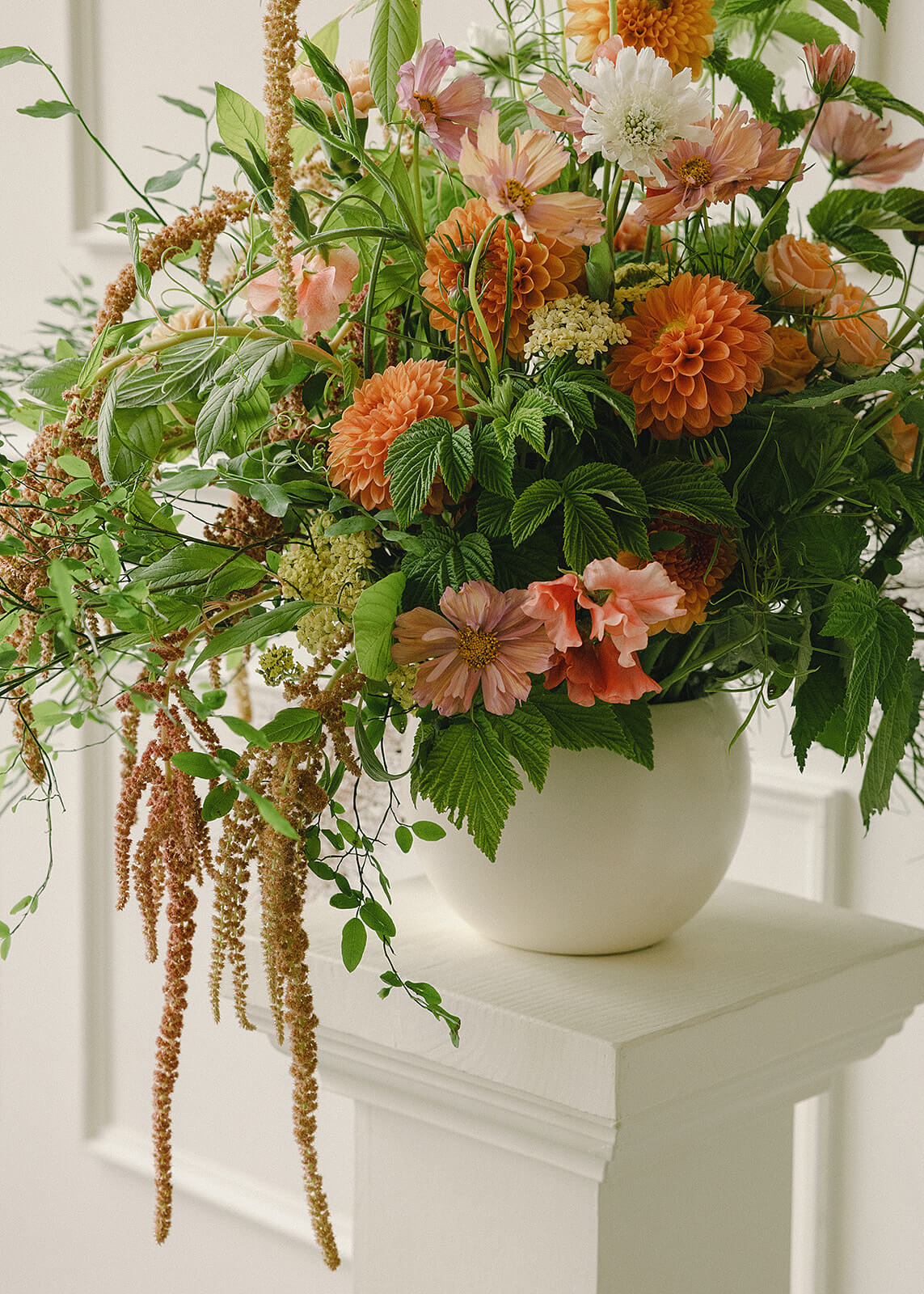 Detail of floral arrangement with orange dahlias, cosmos, and greenery at Tendue Portland