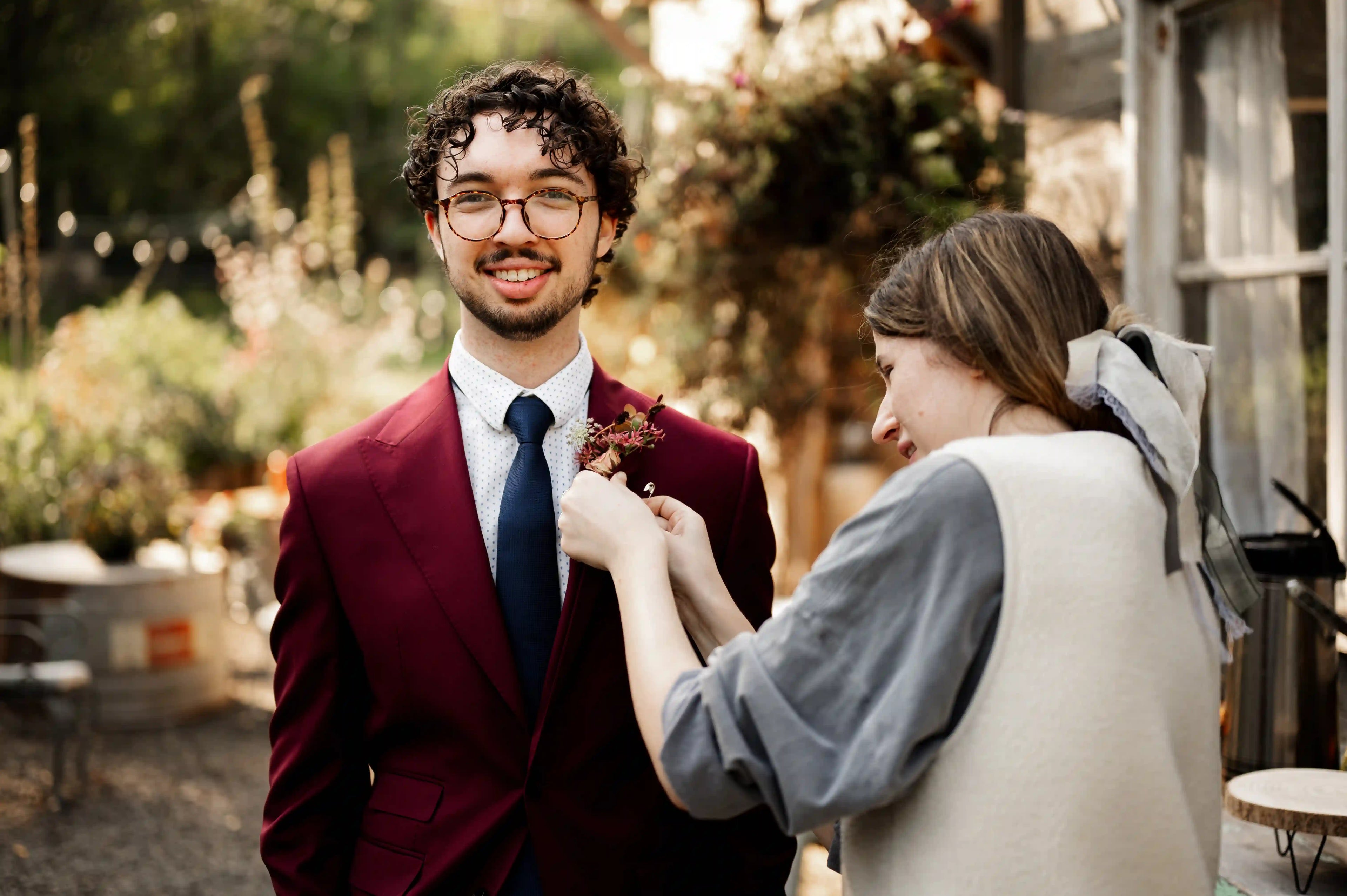 Florist from Kvetka Flower pinning boutonniere on groomsman’s suit — custom wedding flowers in Portland