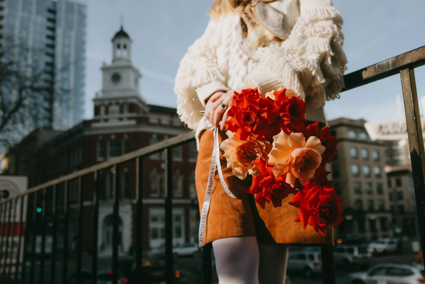 Woman holding vibrant roses bouquet with Portland cityscape