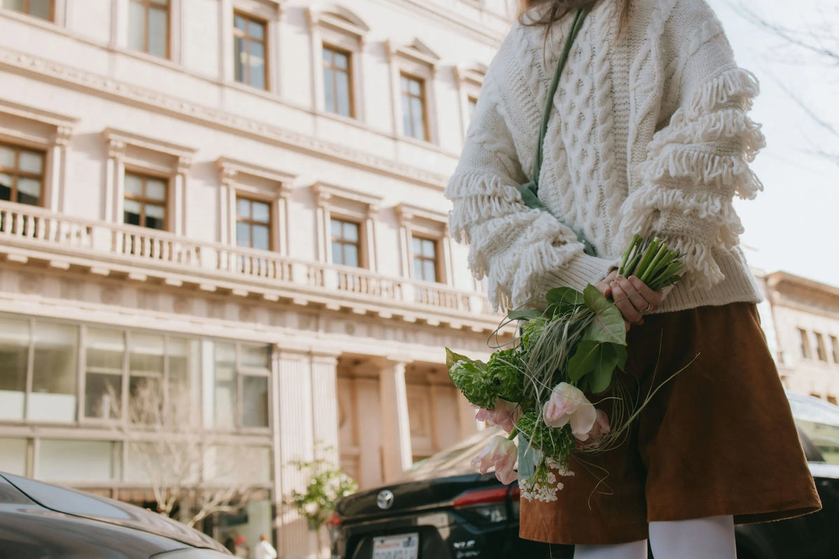 Woman with wild green bouquet against the city architecture