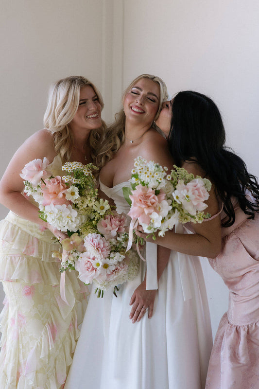 A happy moment at a Portland wedding, with the bride and bridesmaids holding delicate bouquets by Kvetka Flower.