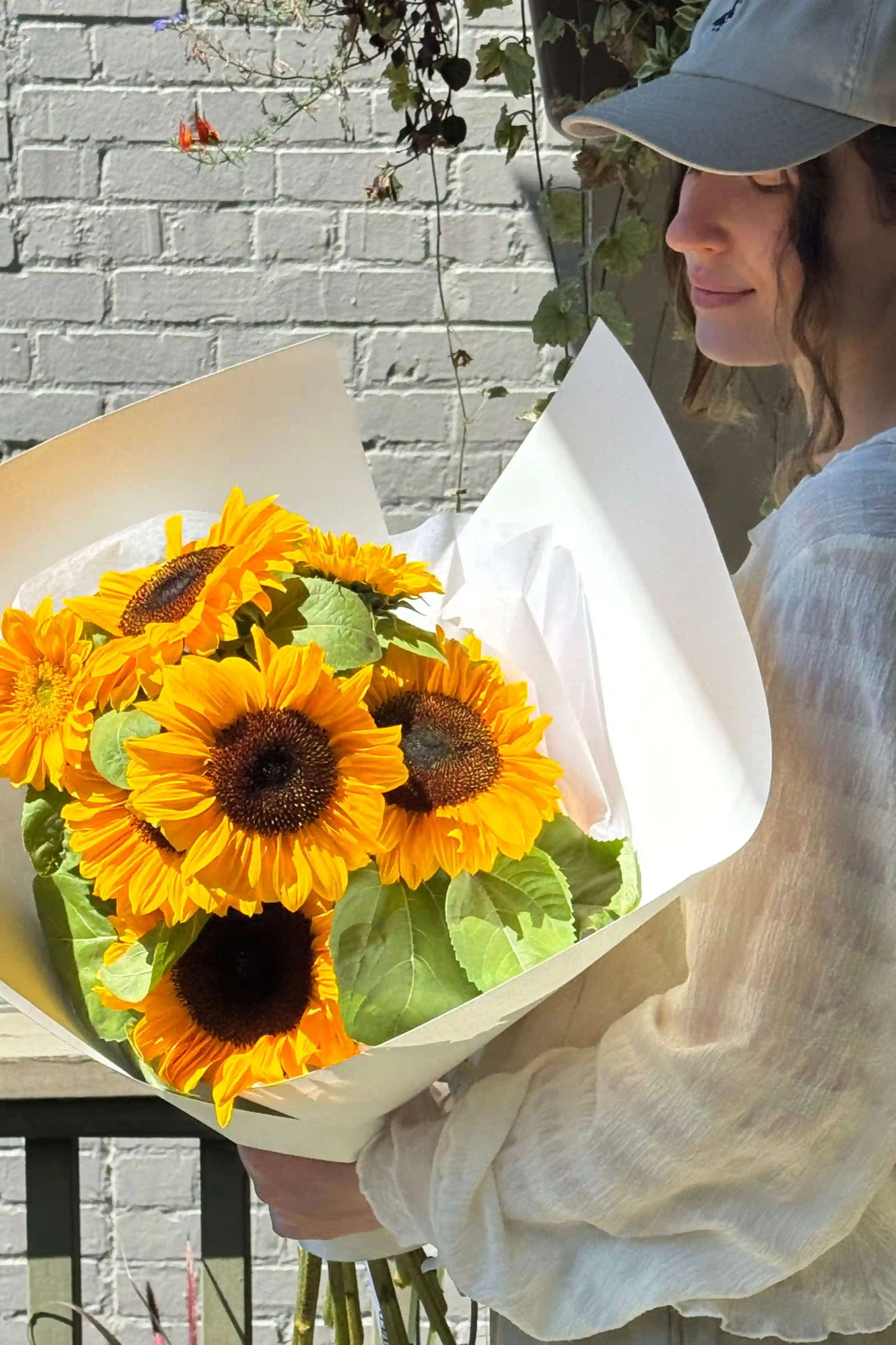 Small sunflower bouquet held in hands, wrapped in soft white paper – Sun Day by Kvetka Flower, Portland Oregon