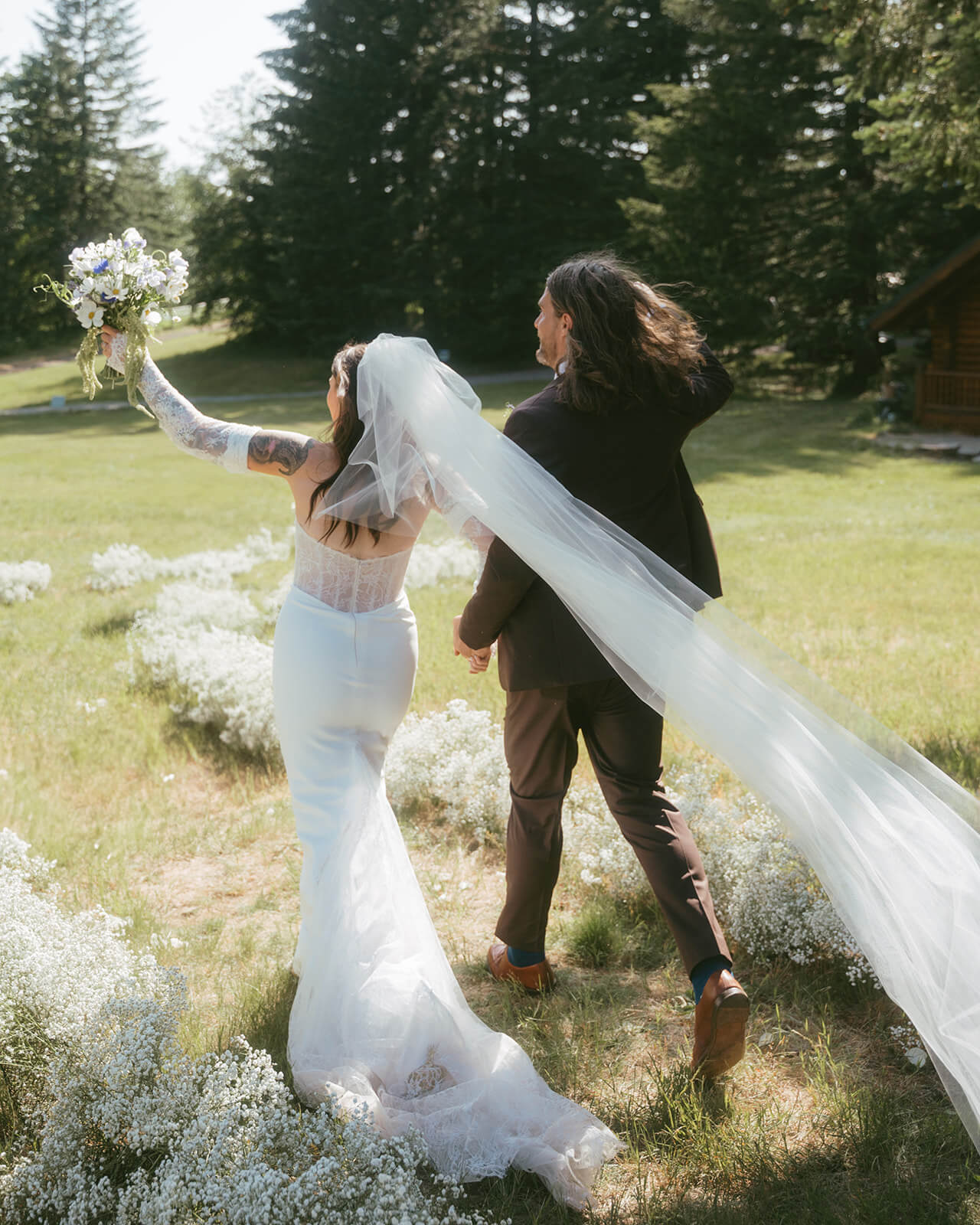 Bride and groom walking hand in hand through mountain meadow with bridal bouquet by Kvetka Flower in Portland OR