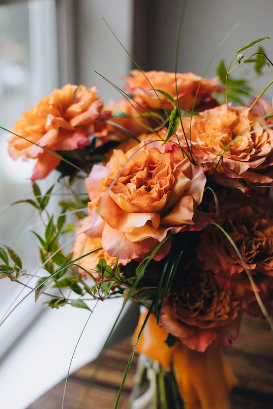 Close-up of fresh orange roses with seasonal greenery hand-tied by Kvetka Flower Portland