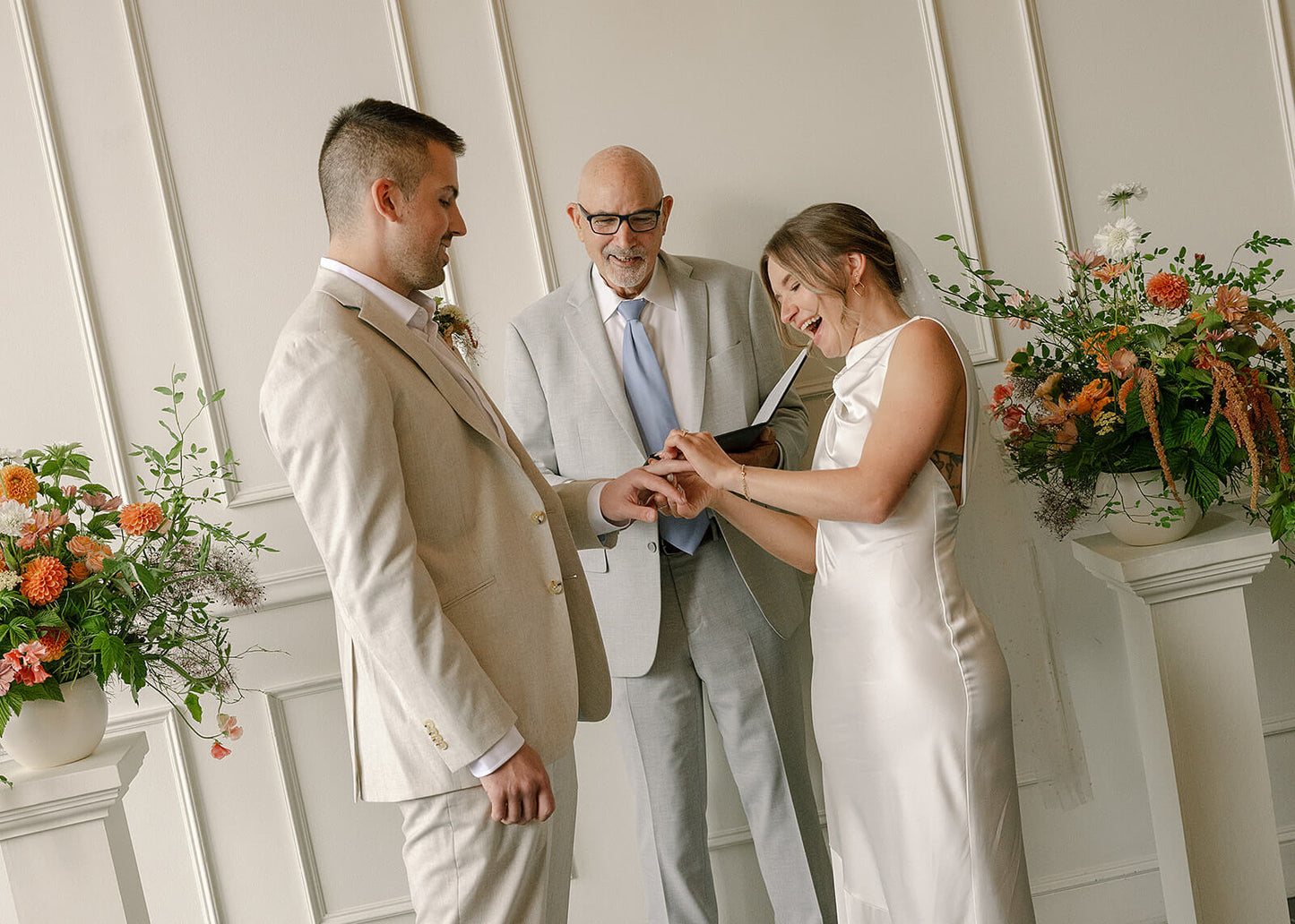 Bride and groom exchanging rings during Portland wedding with flower pillars by Kvetka