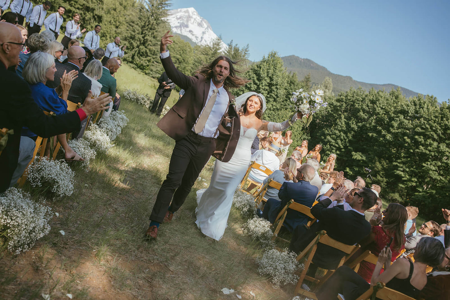 Joyful wedding ceremony exit with bride and groom holding bouquet by Kvetka Flower Portland OR