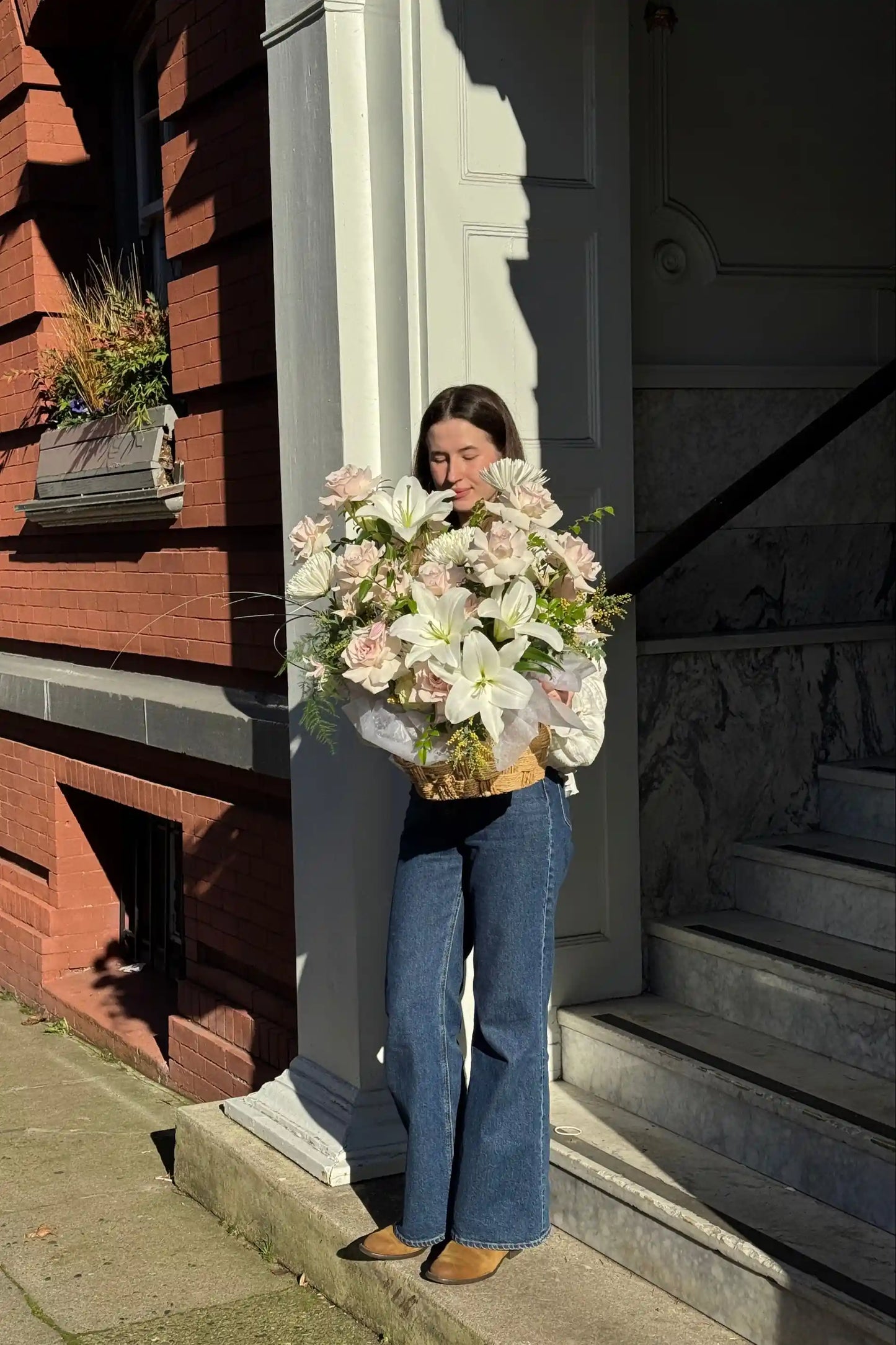 Woman holding large romantic flower basket with roses and lilies Portland Oregon Kvetka Flower