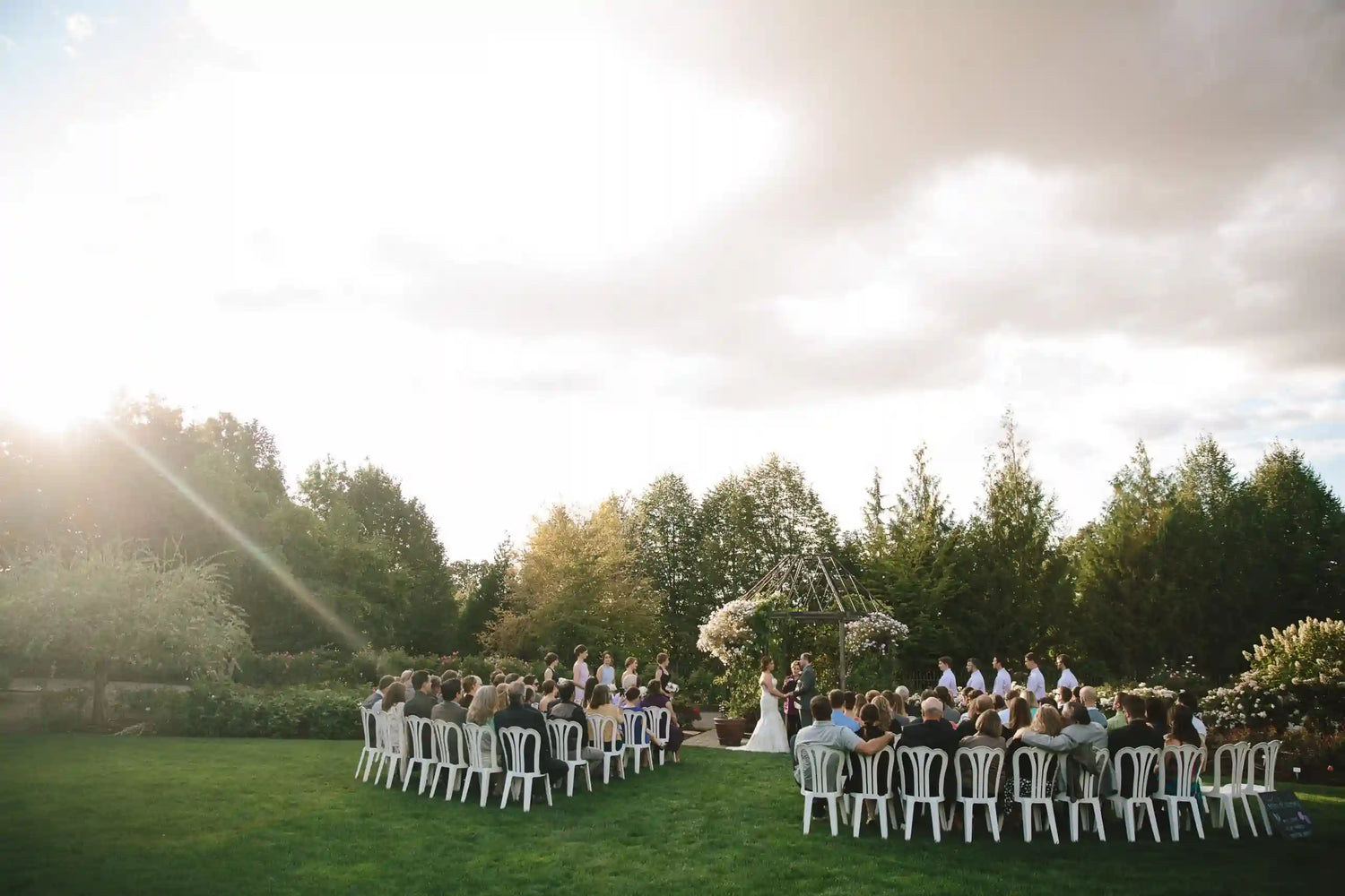 Outdoor wedding ceremony with guests seated on a grassy lawn.