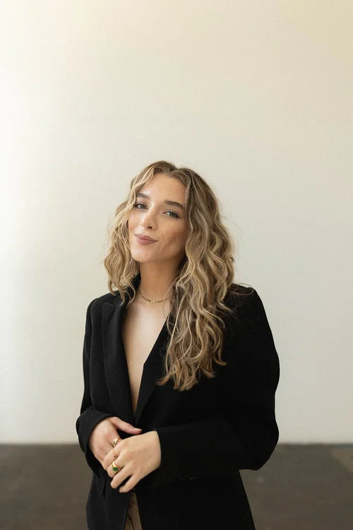 Woman wearing a black blazer against a plain background