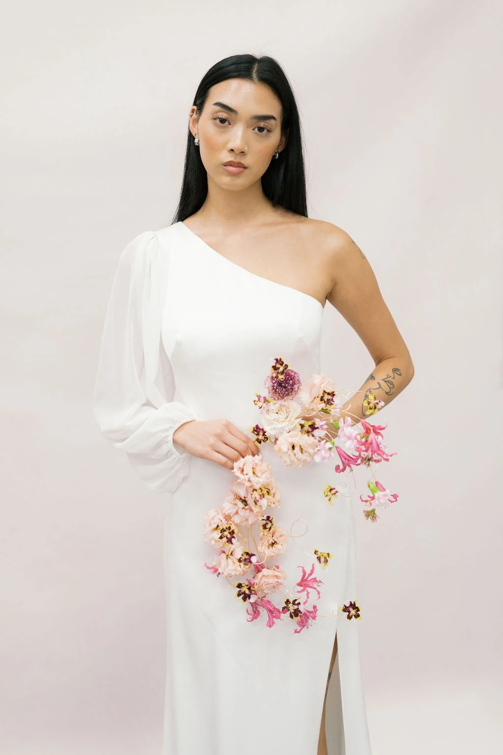 Bride holding sculptural cascading bouquet with miniature orchids and carnations by Kvetka Flower Portland OR