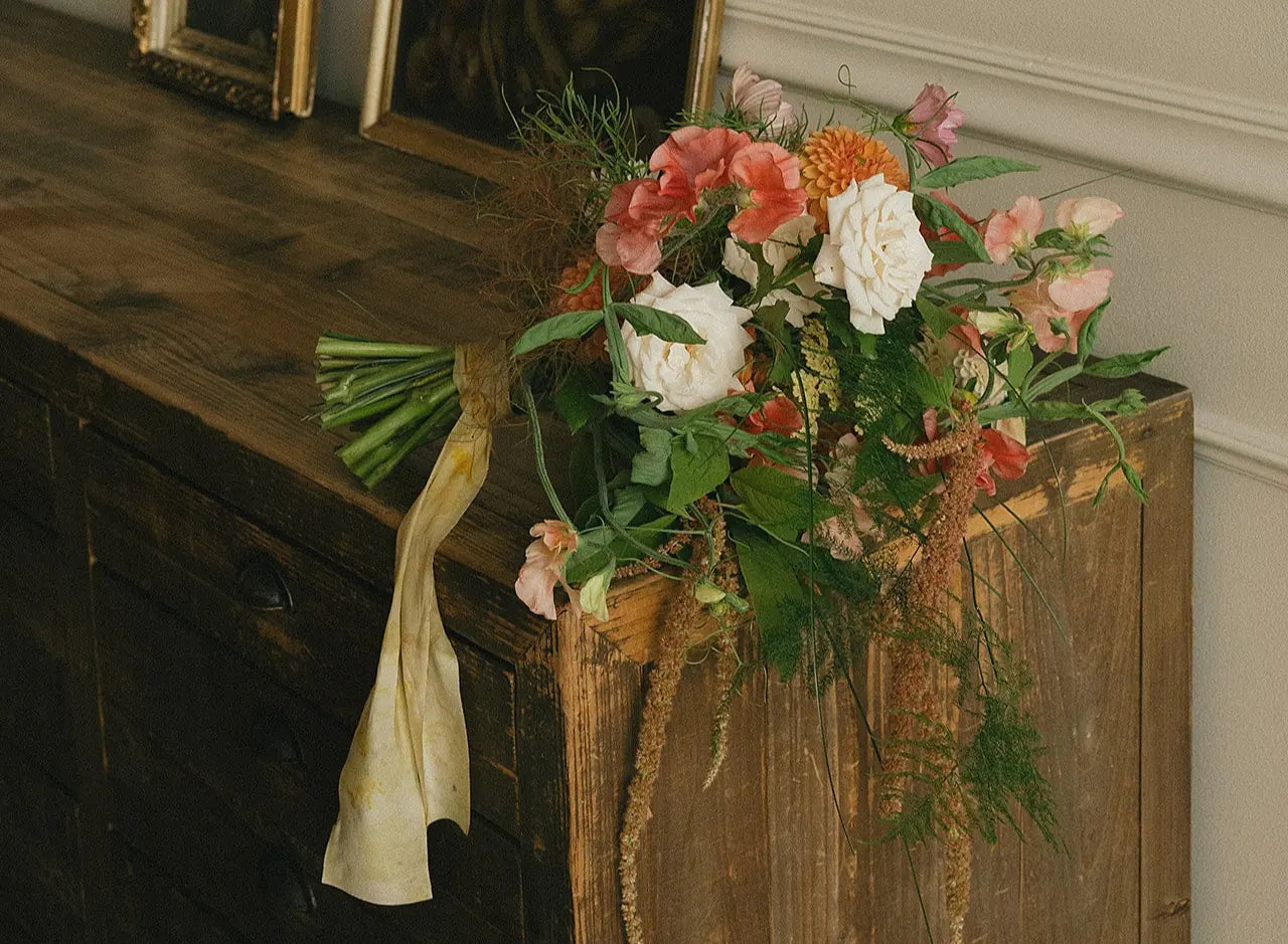 Floral arrangement on a wooden surface with a white wall background