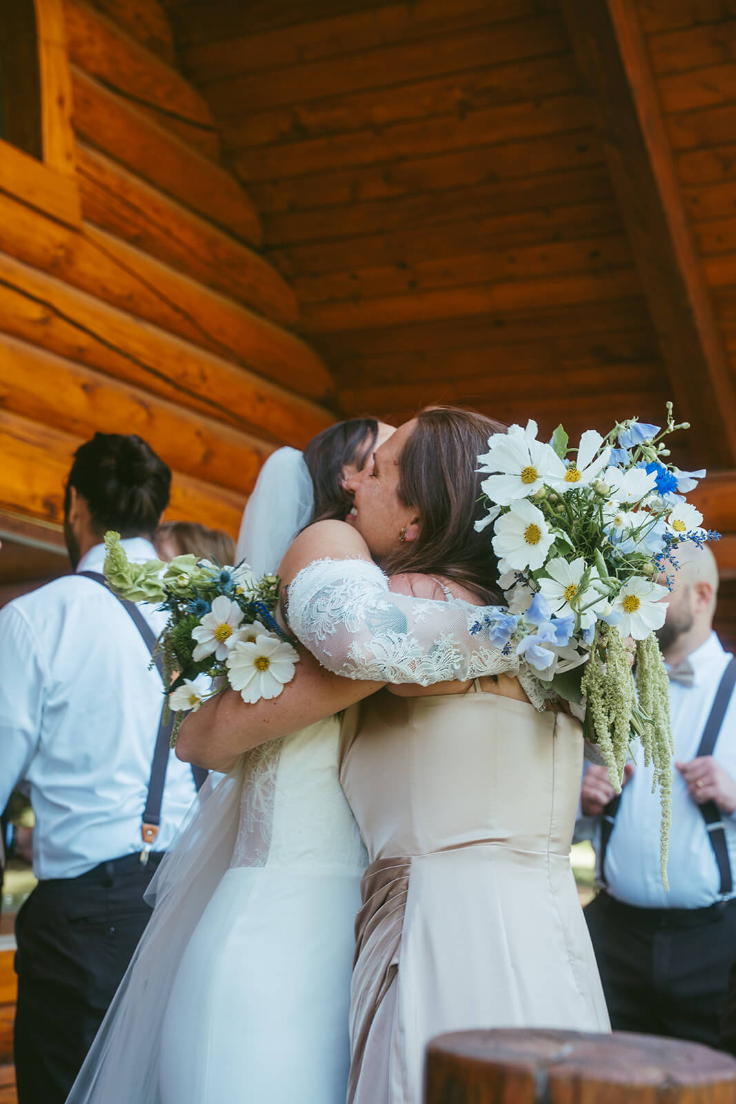 Bride hugging bridesmaid holding white and blue bouquet by Kvetka Flower Portland OR