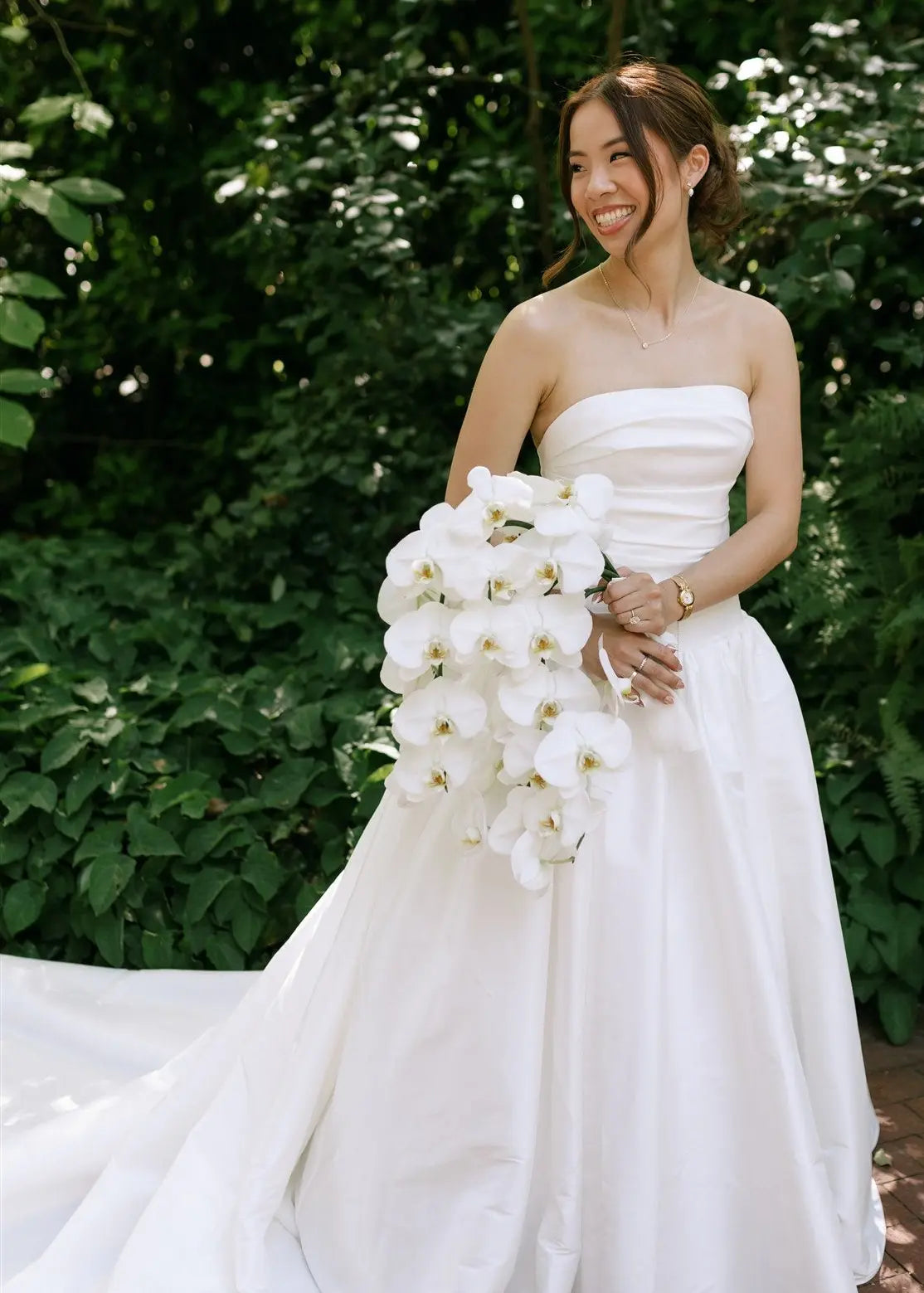 Bride holding a cascading mono bouquet of white orchids | Kvetka Flower wedding florist in Portland OR