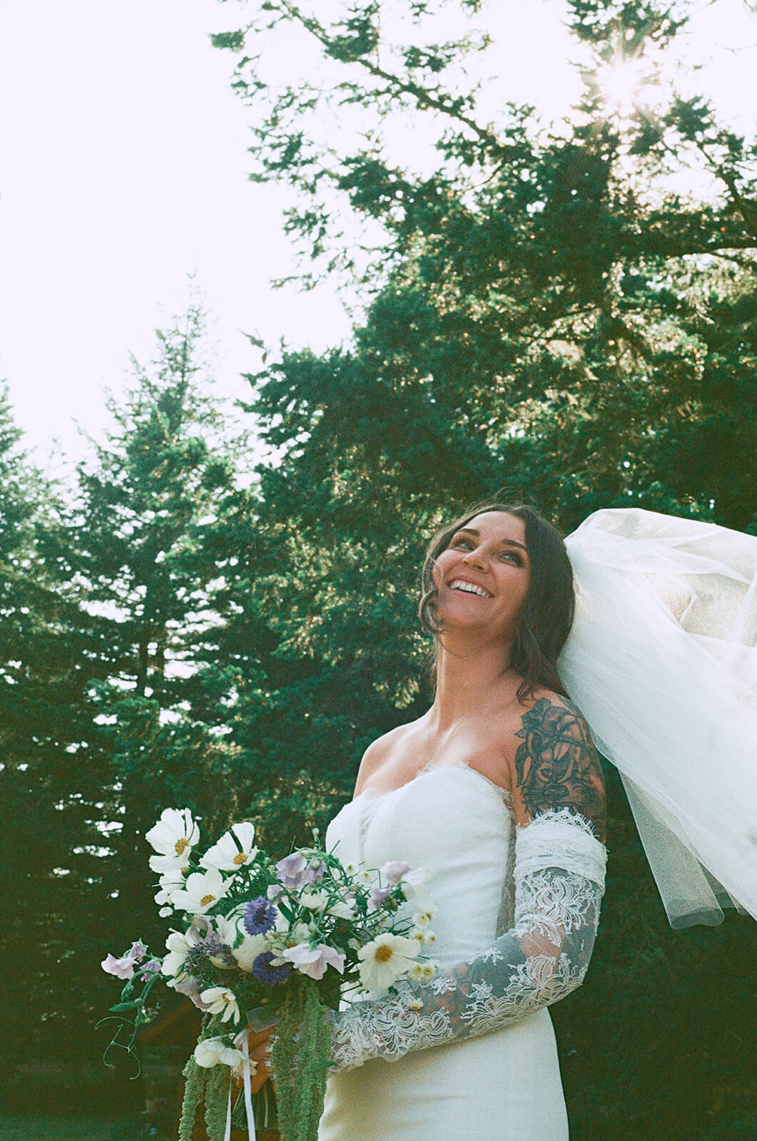 Bride smiling with lace sleeves holding wildflower bridal bouquet by Kvetka Flower Portland OR