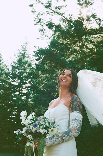 Bride smiling with lace sleeves holding wildflower bridal bouquet by Kvetka Flower Portland OR