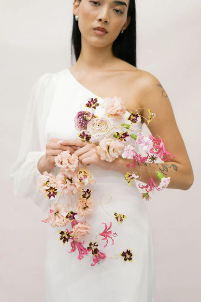 Close-up of wearable wire-frame bridal bouquet with blush lisianthus and burgundy mini orchids by Kvetka Flower