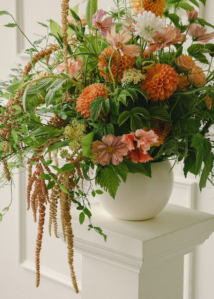 Detail of floral arrangement with orange dahlias, cosmos, and greenery at Tendue Portland
