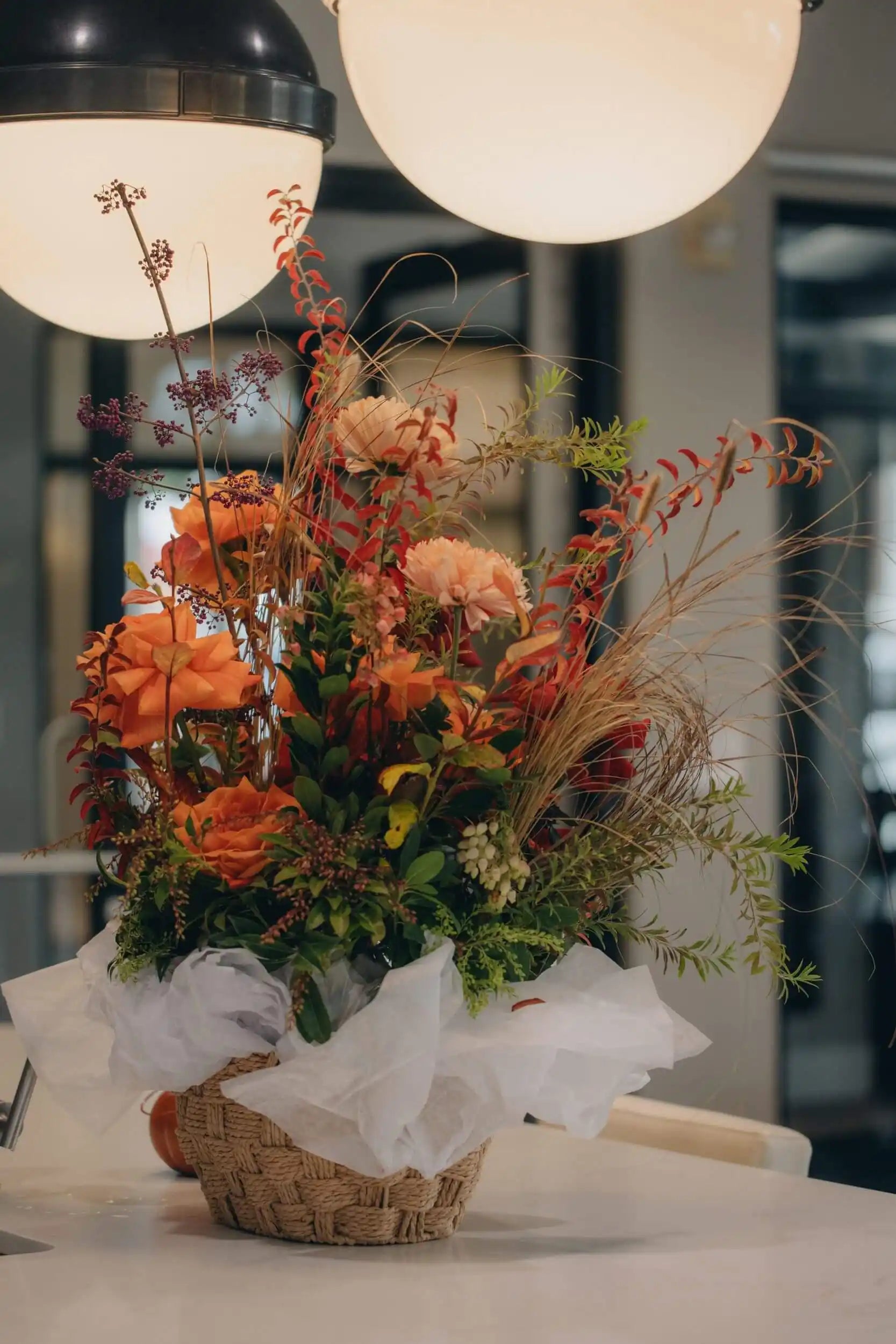 Garden-style flower basket with red roses, orange dahlias, and autumn foliage by Portland florist