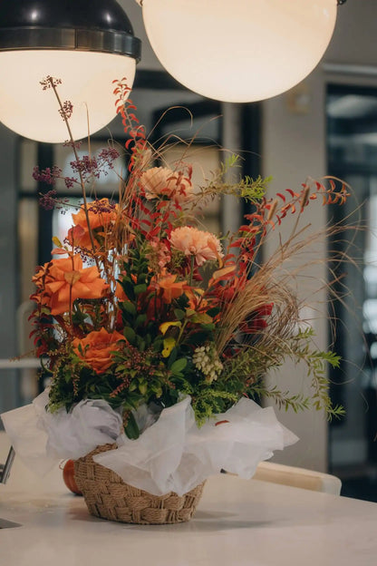 Garden-style flower basket with red roses, orange dahlias, and autumn foliage by Portland florist