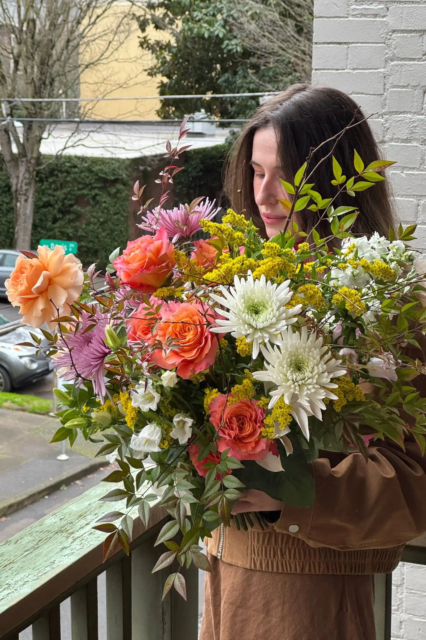 Woman holding large fresh seasonal bouquet bright palette orange roses Portland florist Kvetka Flower