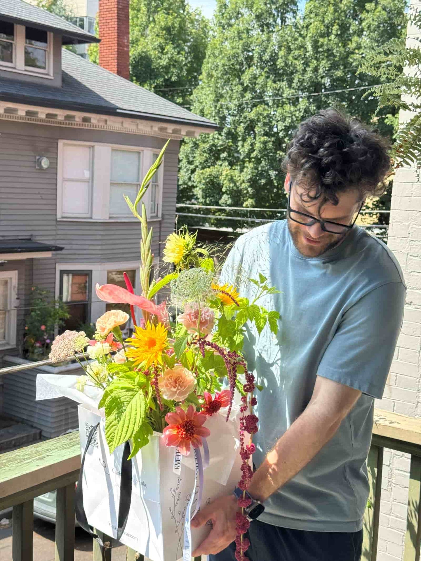 Florist holding a Fresh Seasonal Bouquet with sunflowers, garden roses, dahlias and amaranth in a Kvetka Flower bag before delivery in Portland, Oregon