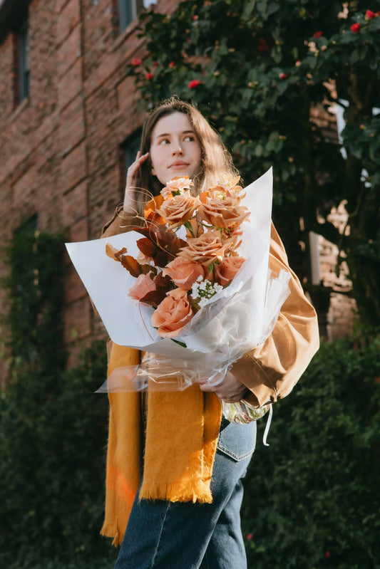 Woman holding luxury beige roses and orchids bouquet