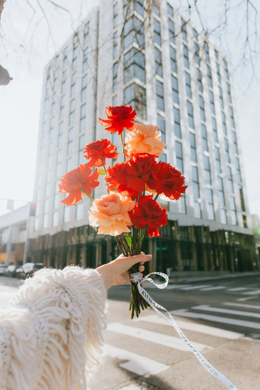 Hand holding vibrant roses bouquet against Portland skyline