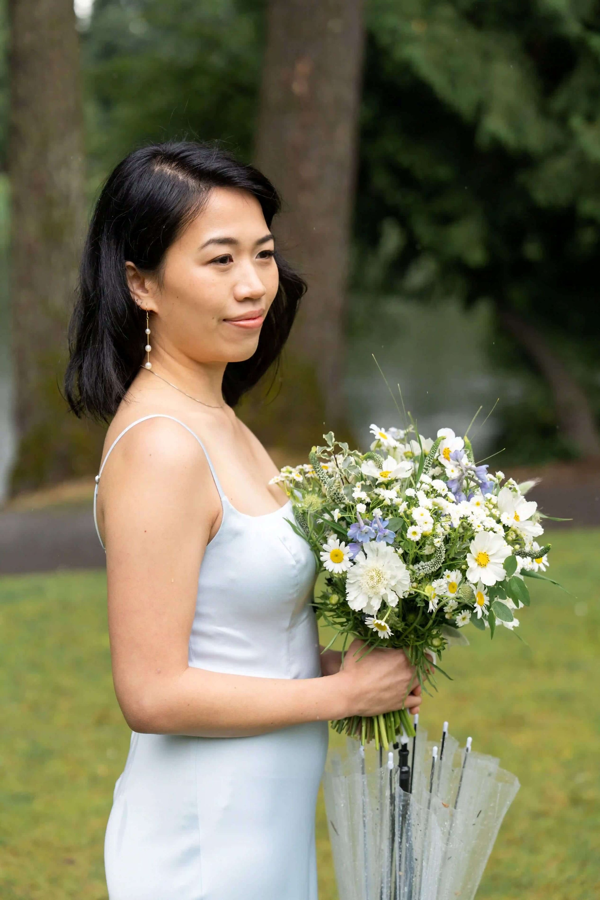 Bridesmaid holding a delicate white and blue bouquet by Kvetka Flower with chamomile flowers in Portland, OR