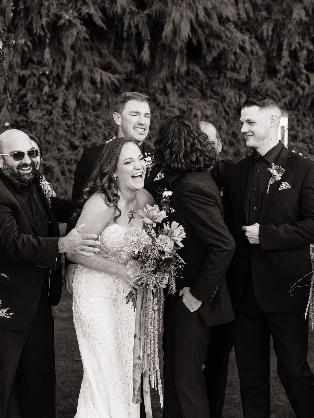 Candid photo of bride laughing with groomsmen wearing dahlia boutonnieres at Langdon Farms.