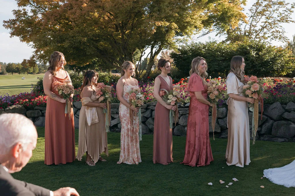 View of bridesmaids in mismatched dresses during the wedding ceremony.