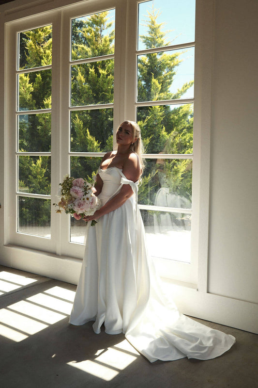 Full-length bridal portrait with a wedding bouquet by Kvetka Flower in a light-filled room at Redland Family Farm.