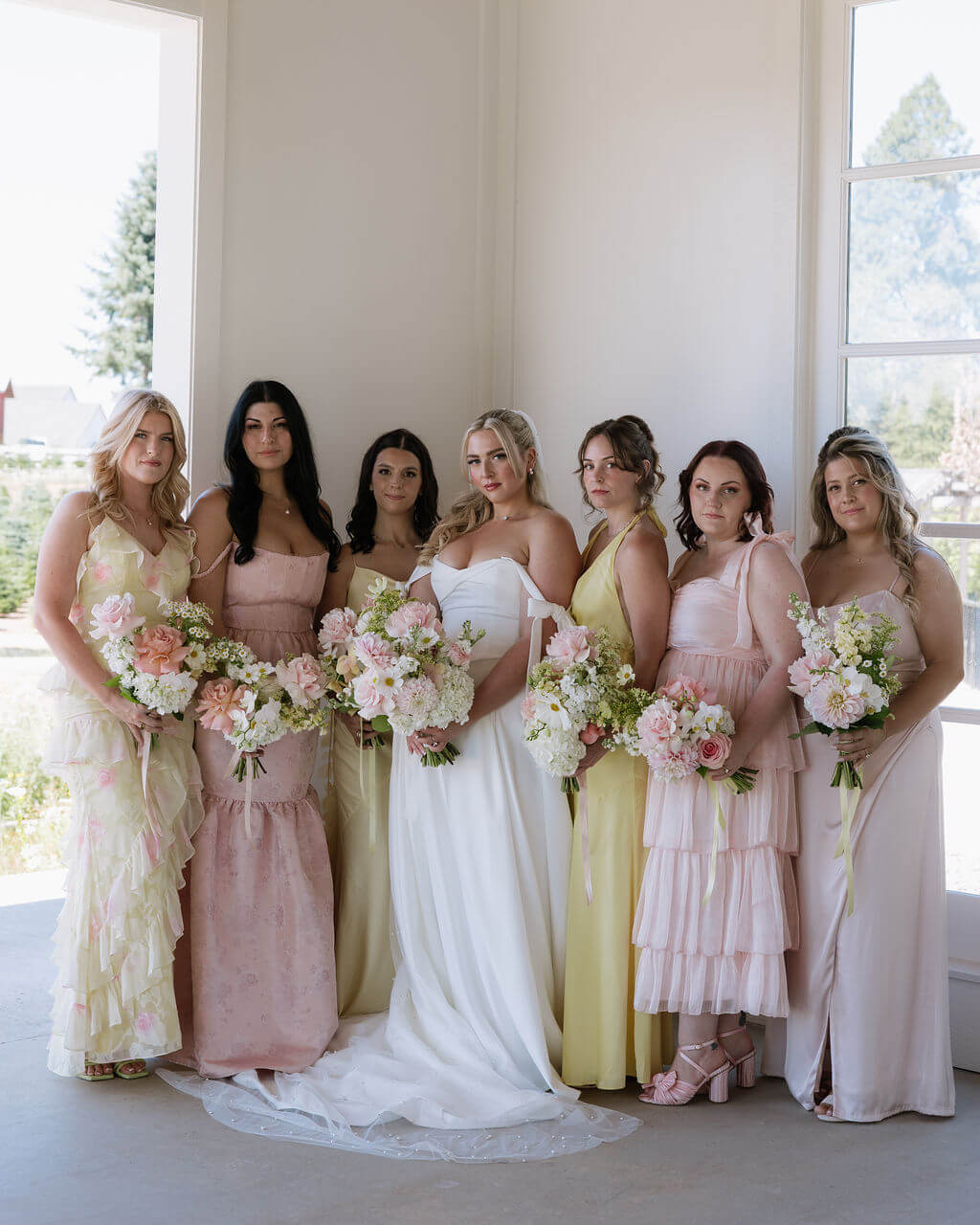 Bride and bridesmaids holding pastel-toned wedding bouquets by Kvetka Flower at a wedding in Portland.