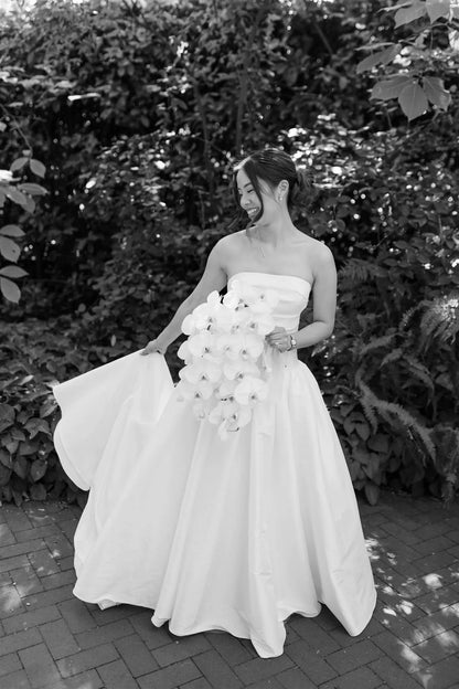 Joyful bride with flowing dress holding white orchid bouquet by Kvetka Flower Portland wedding florist