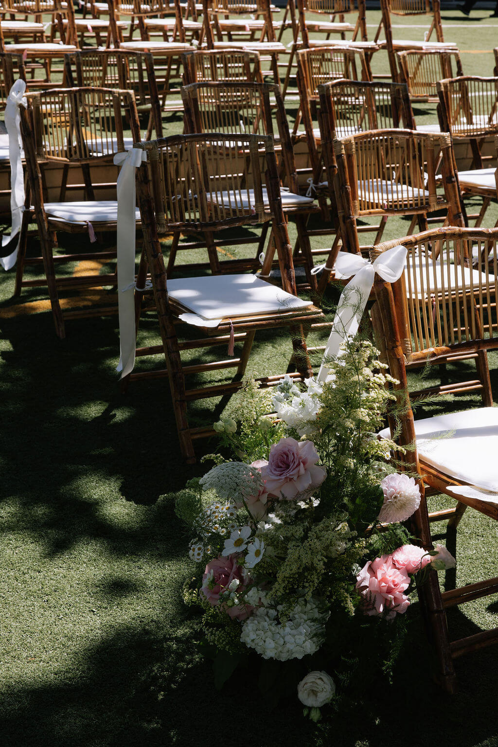 A lush floral arrangement decorating the chairs at a wedding ceremony by Kvetka Flower at Redland Family Farm.