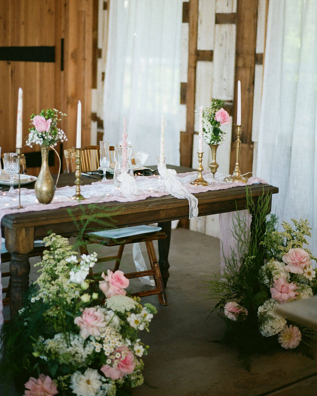 The sweetheart table is decorated with floor arrangements and flowers in vases by Kvetka Flower.