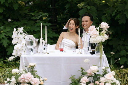 Joyful couple at sweetheart table with white orchids and blush roses floor arrangements by Kvetka Flower Portland