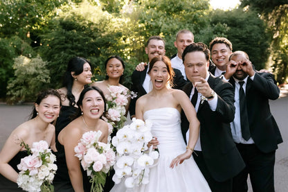 Fun wedding party photo with bride holding white orchid bouquet and bridesmaids with blush rose bouquets by Kvetka Flower