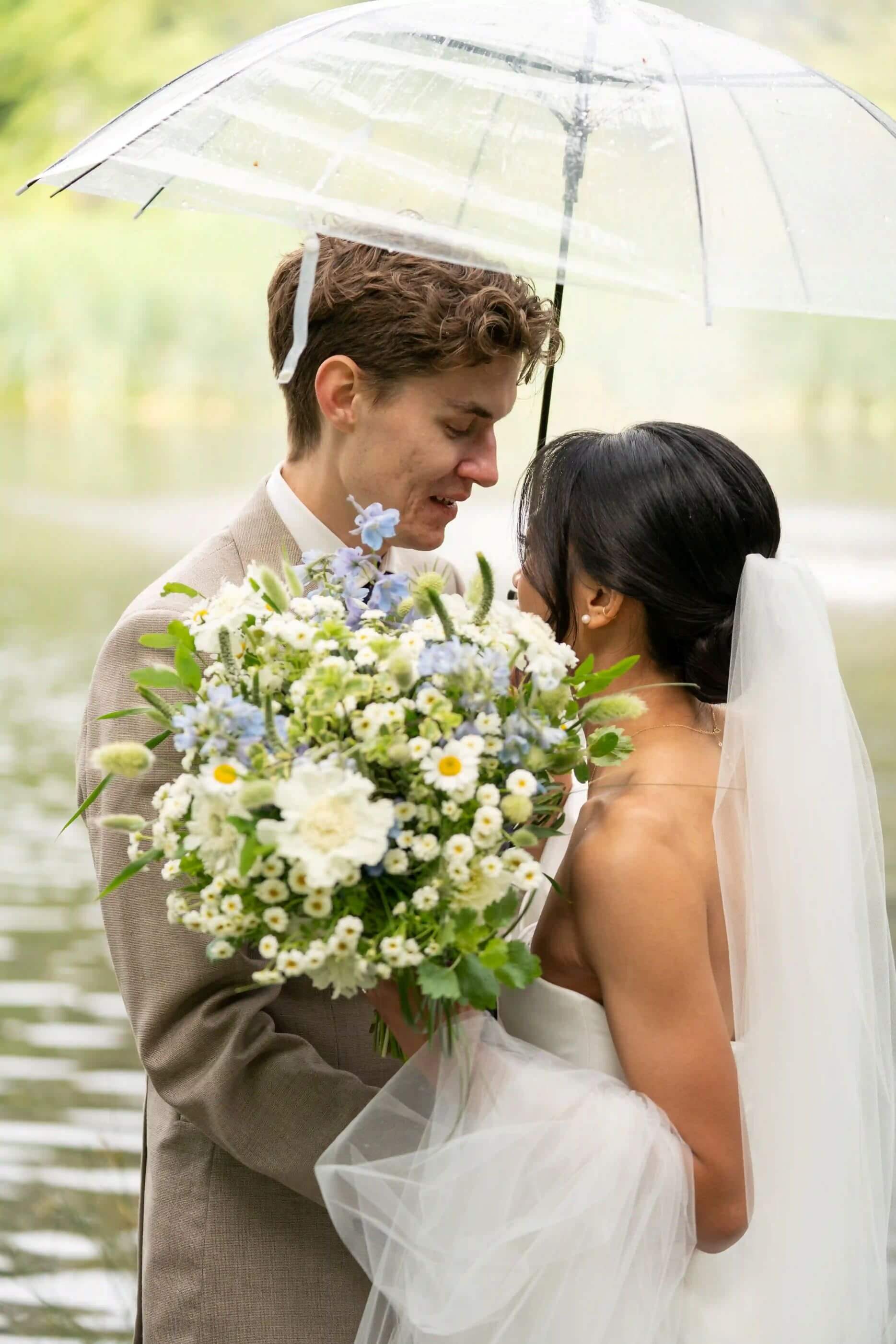Close-up of bride and groom under an umbrella with Kvetka Flower wedding bouquet in Portland, OR