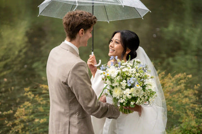 Bride holding an umbrella and smiling at groom with Kvetka Flower wedding bouquet in Portland, OR