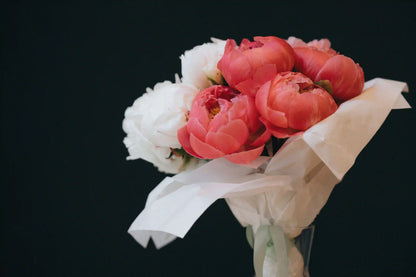 Close-up of bright coral peonies in a hand-wrapped bouquet from Kvetka Flower