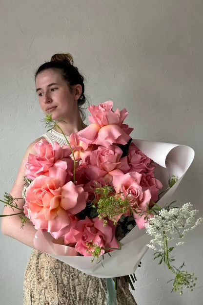 Woman holding luxury bouquet of long stem pink French roses with Queen Anne's Lace by Kvetka Flower Portland