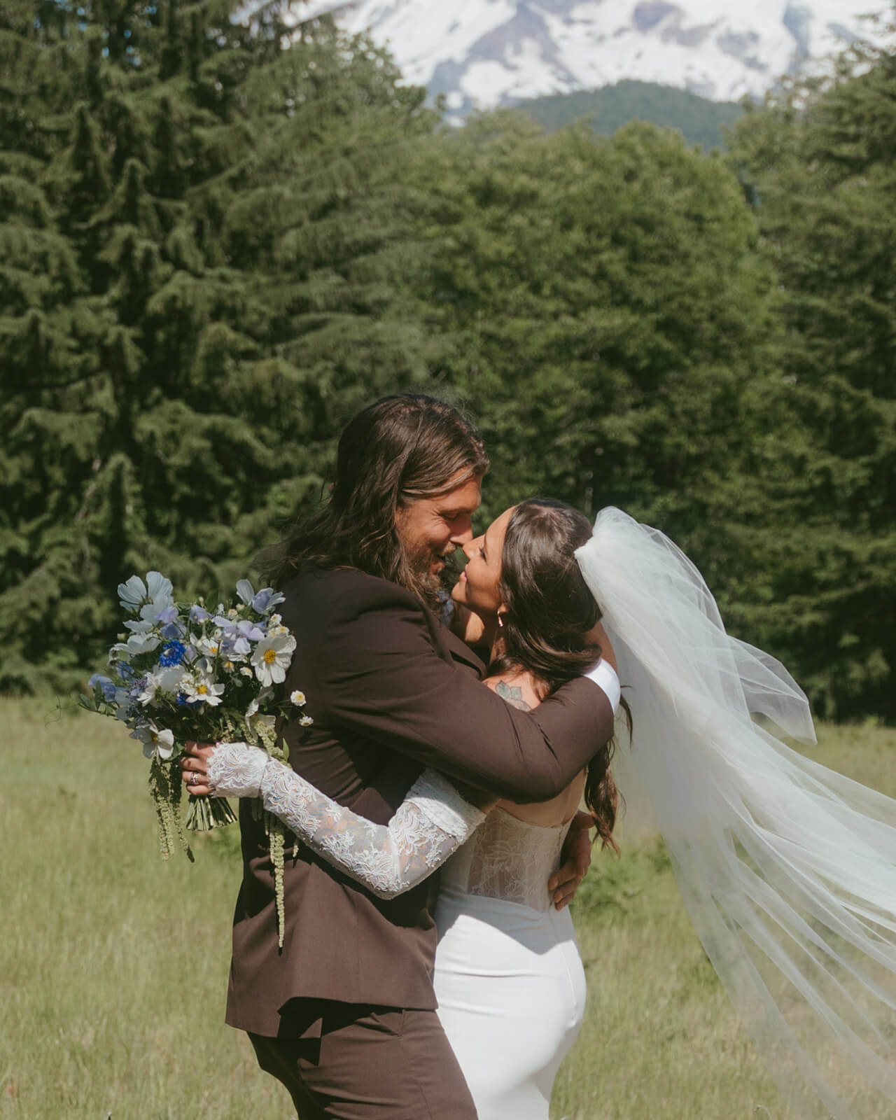 Bride and groom kiss at mountain wedding holding bouquet by Kvetka Flower Portland OR