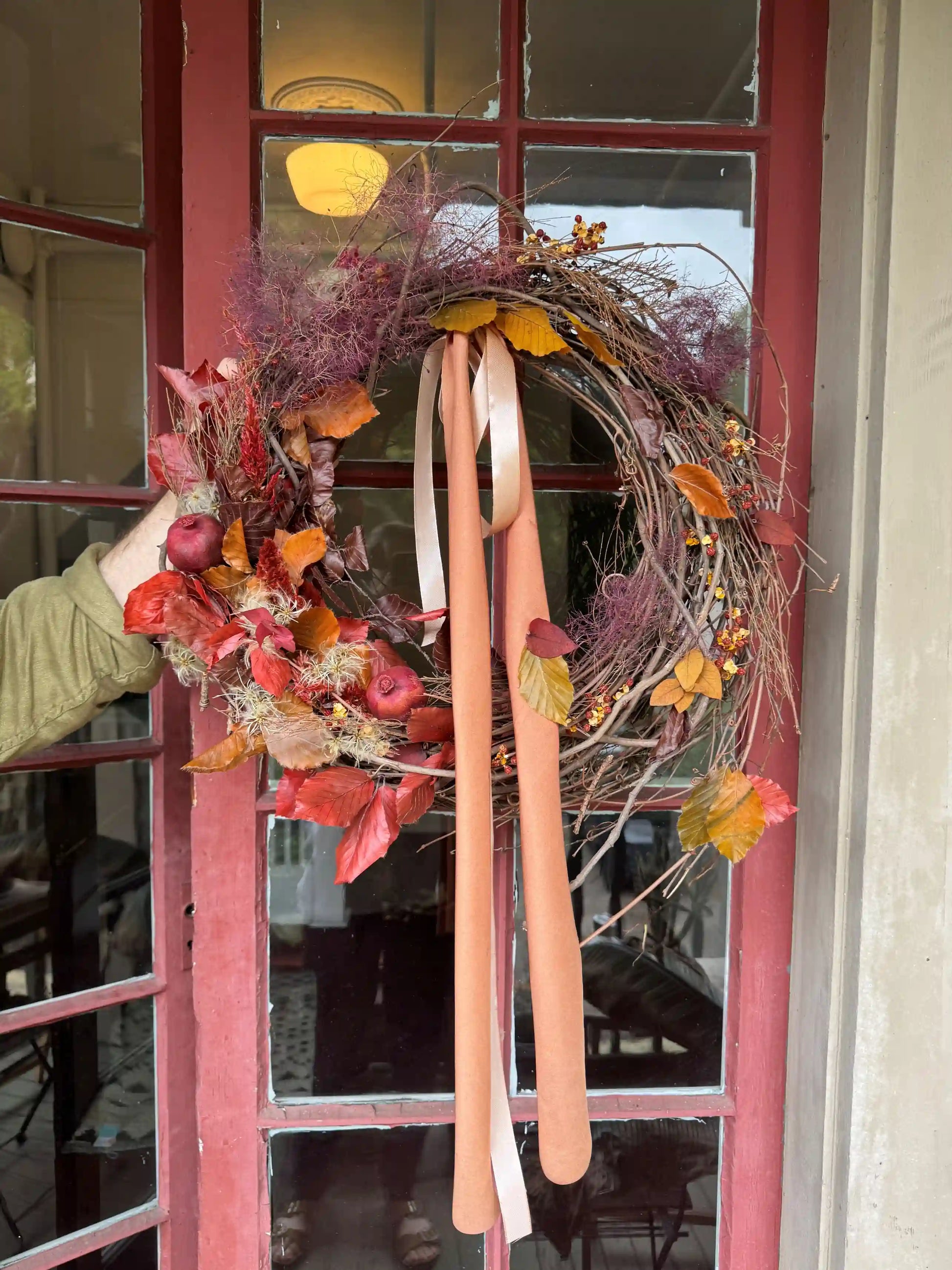 Dried flower wreath with autumn leaves thistles and ribbon on red front door by Kvetka Flower Portland