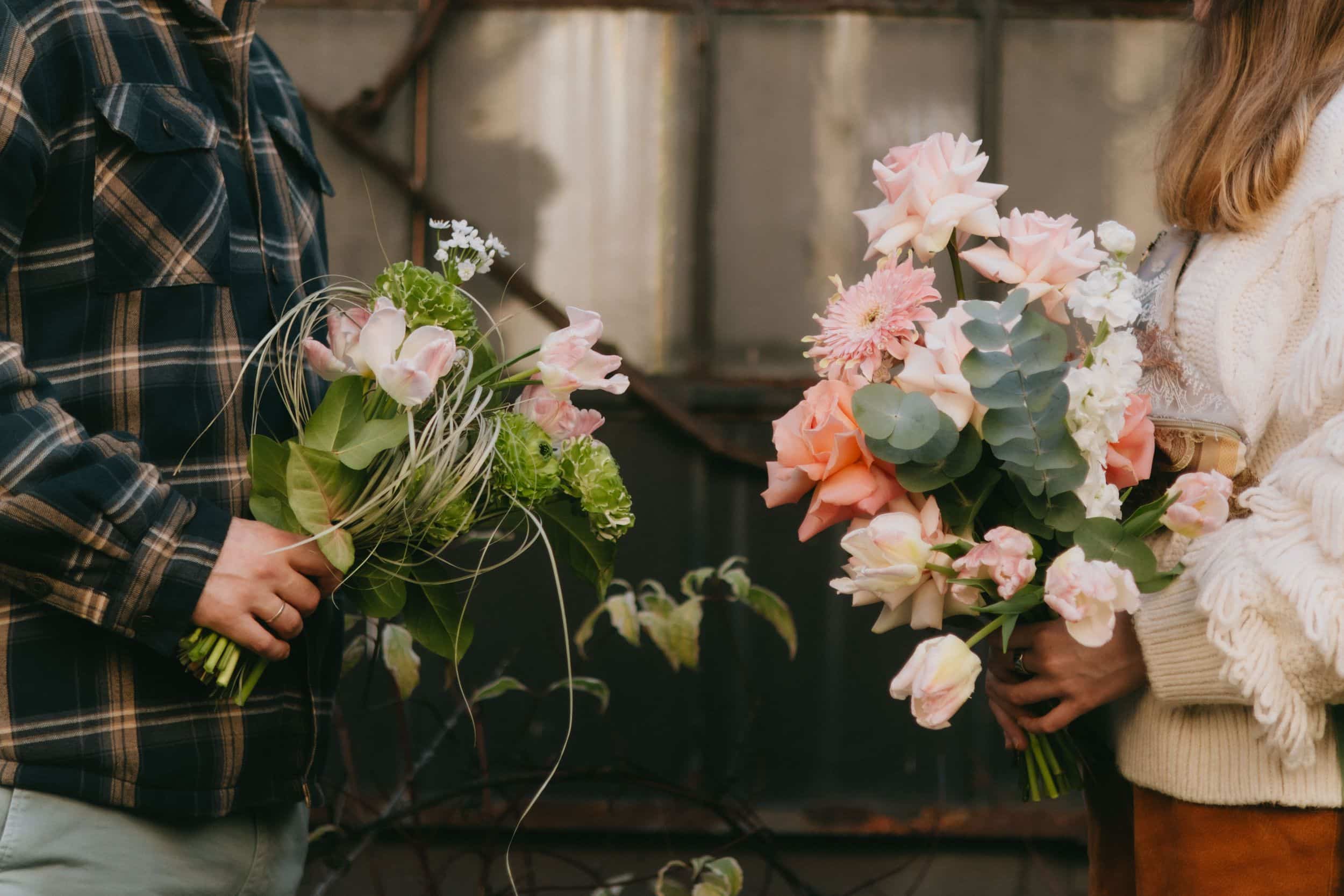A couple exchanging fresh pink and white flower bouquets in soft daylight