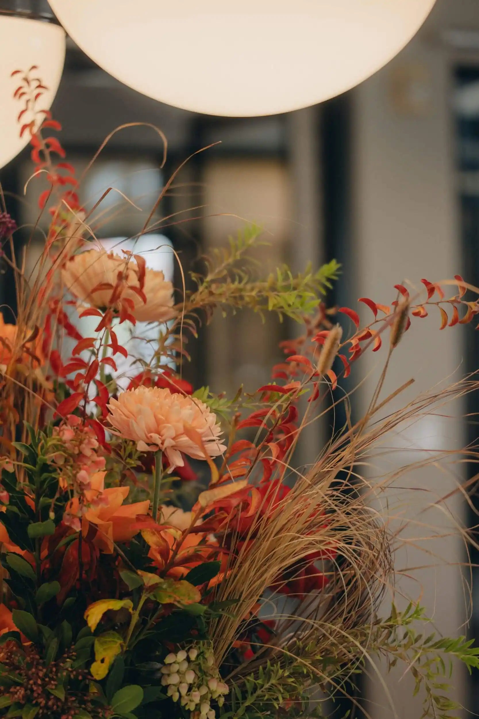 Close-up of seasonal flower basket featuring peach roses, red blooms, and ornamental grasses